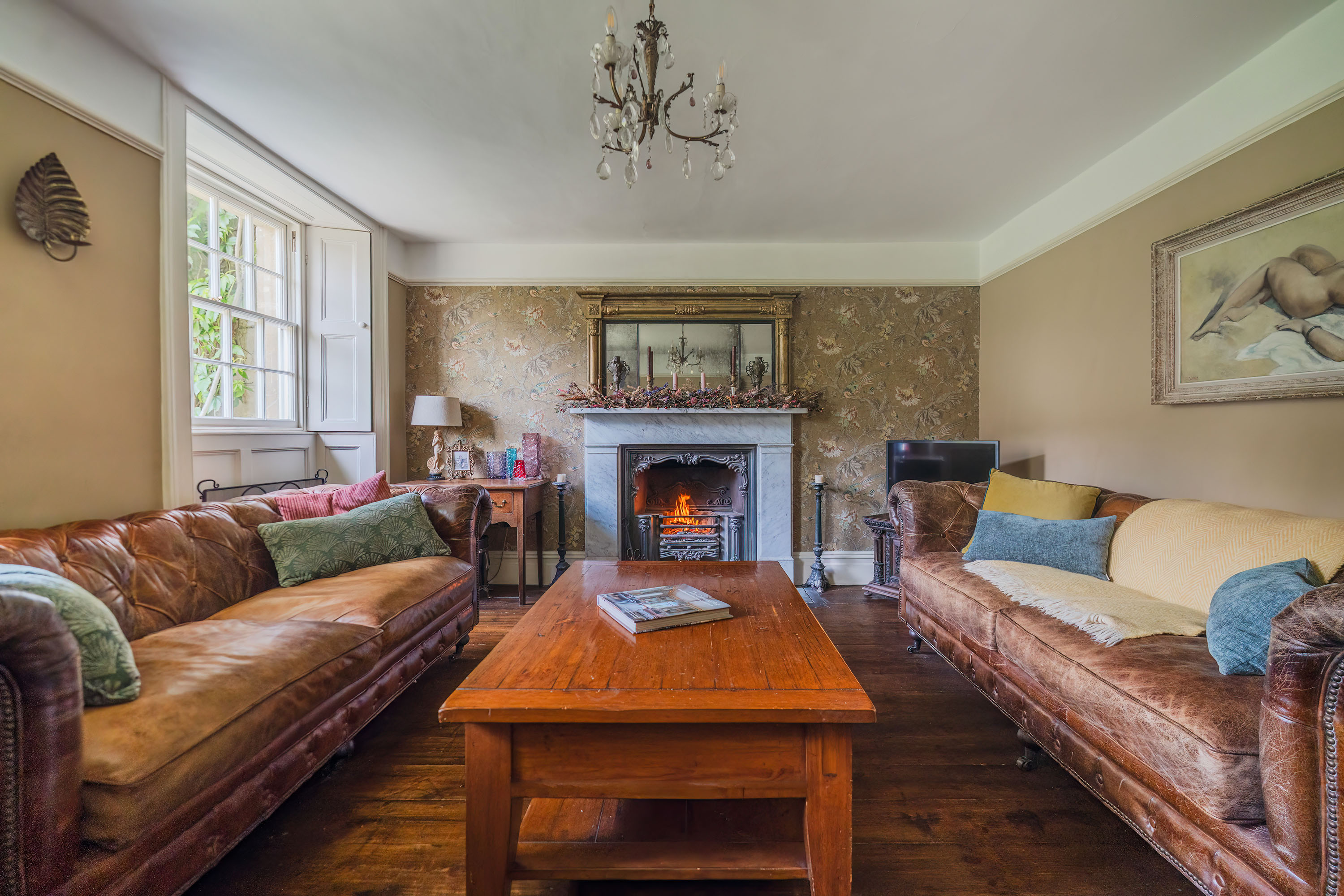 itting room at Doric House with an open fire, leather sofas and timber floorboards, Doulting — Captura Media