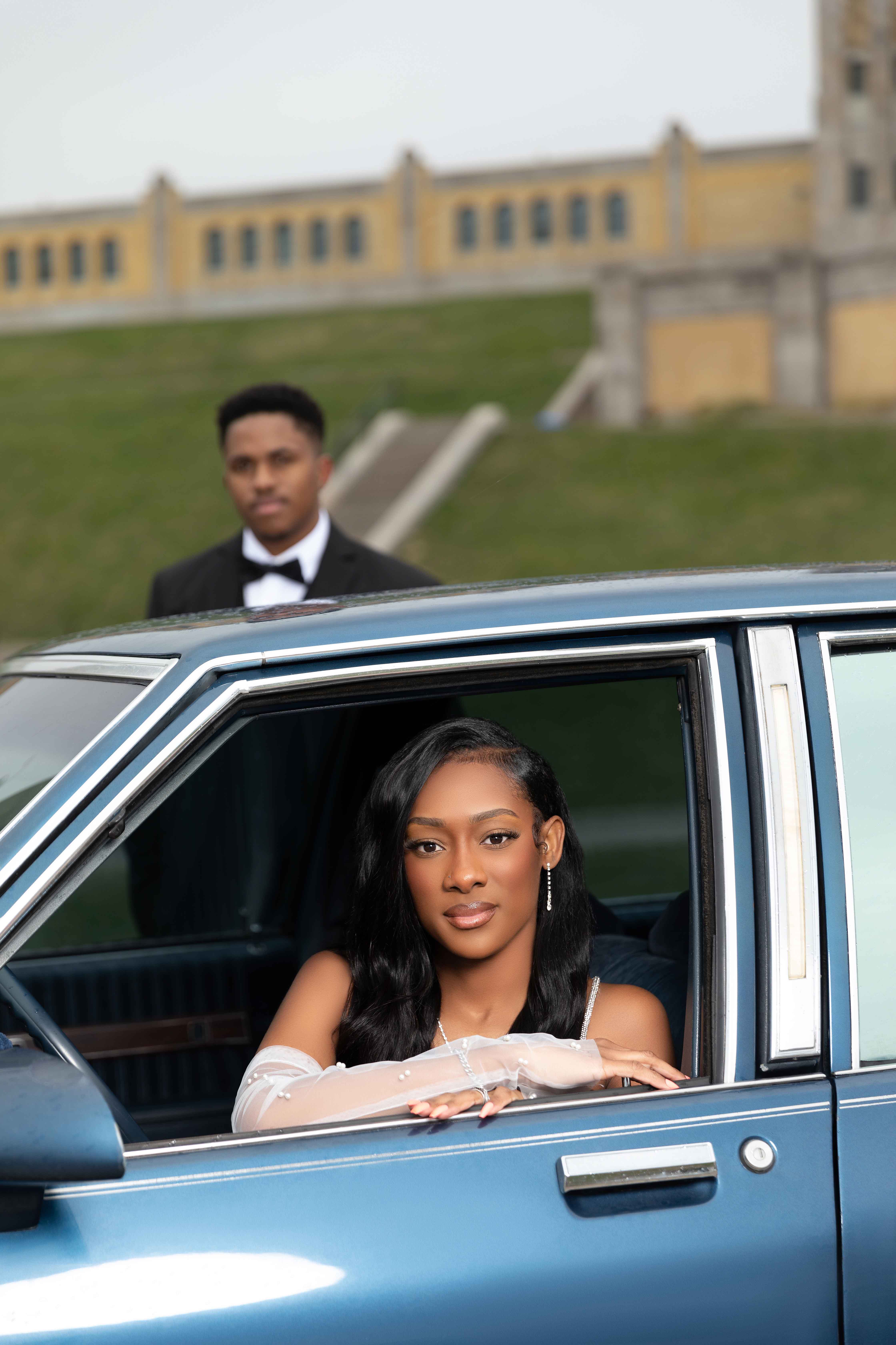Woman sitting in a car with a man standing behind the vehicle