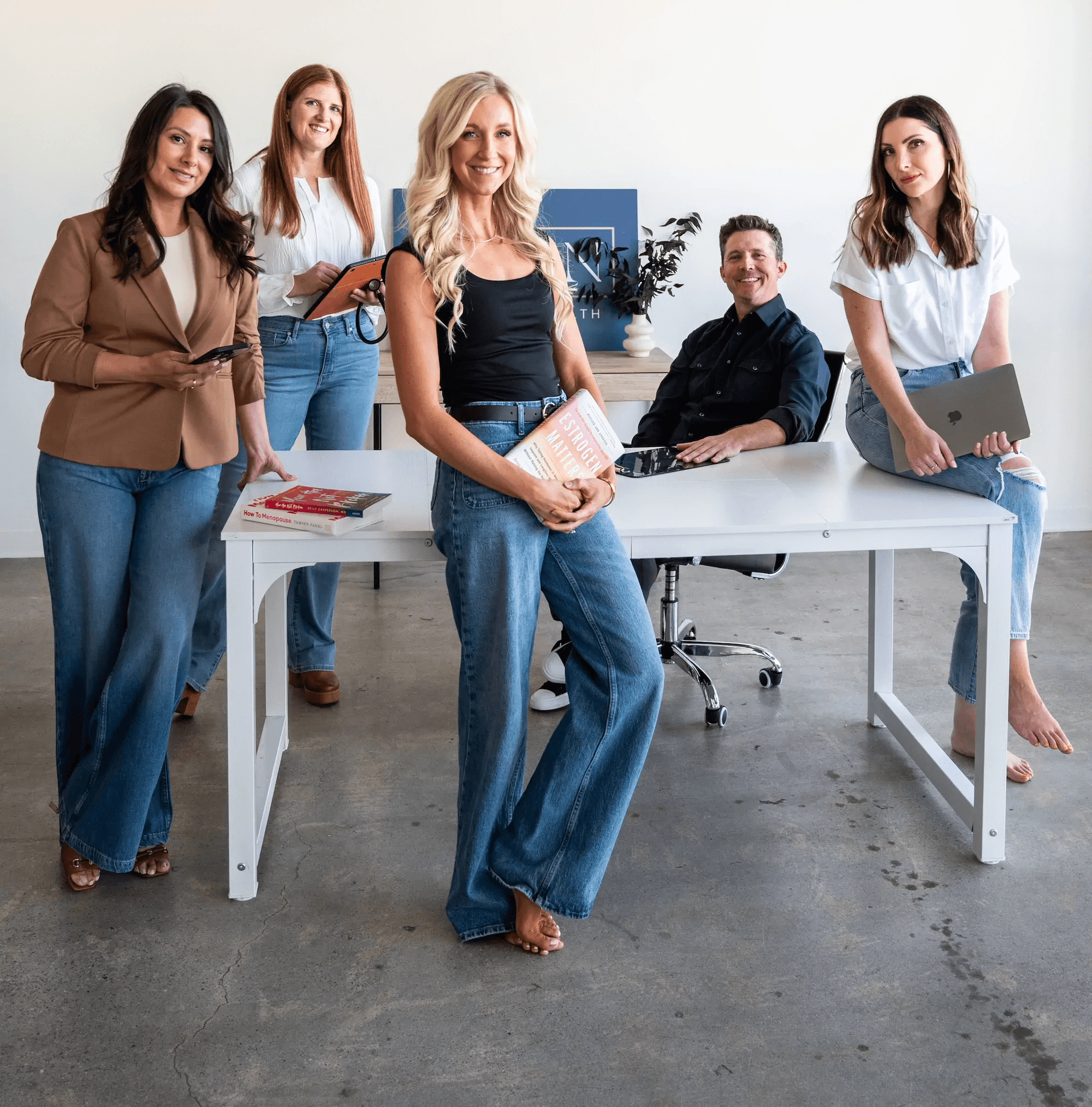 JamJamie Ruiz, Chelsey Galipeau, and other HRMN Health team members seated on a couch, smiling in a casual and welcoming office space.