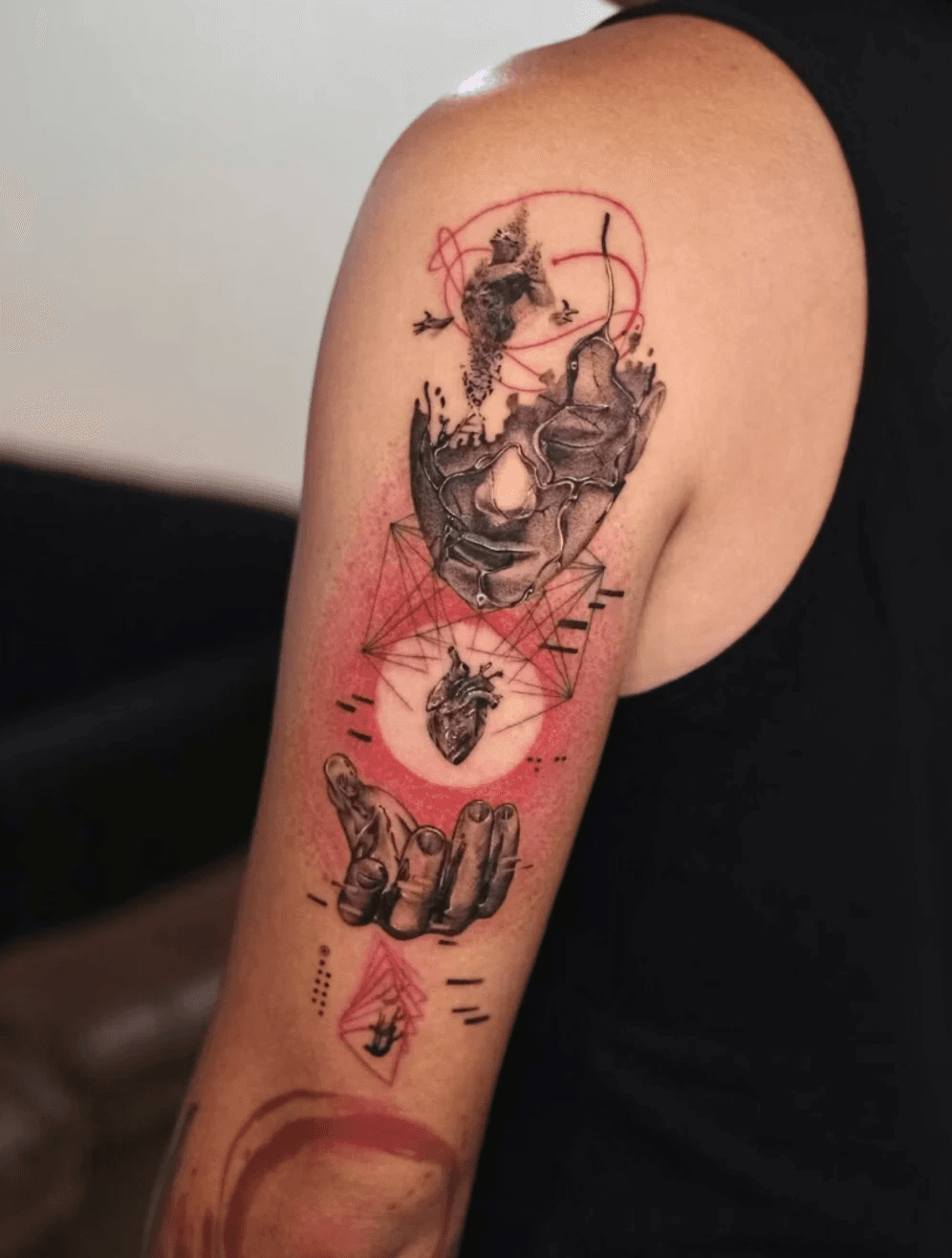 Realistic arm tattoo of broken mask, heart, and red accents.