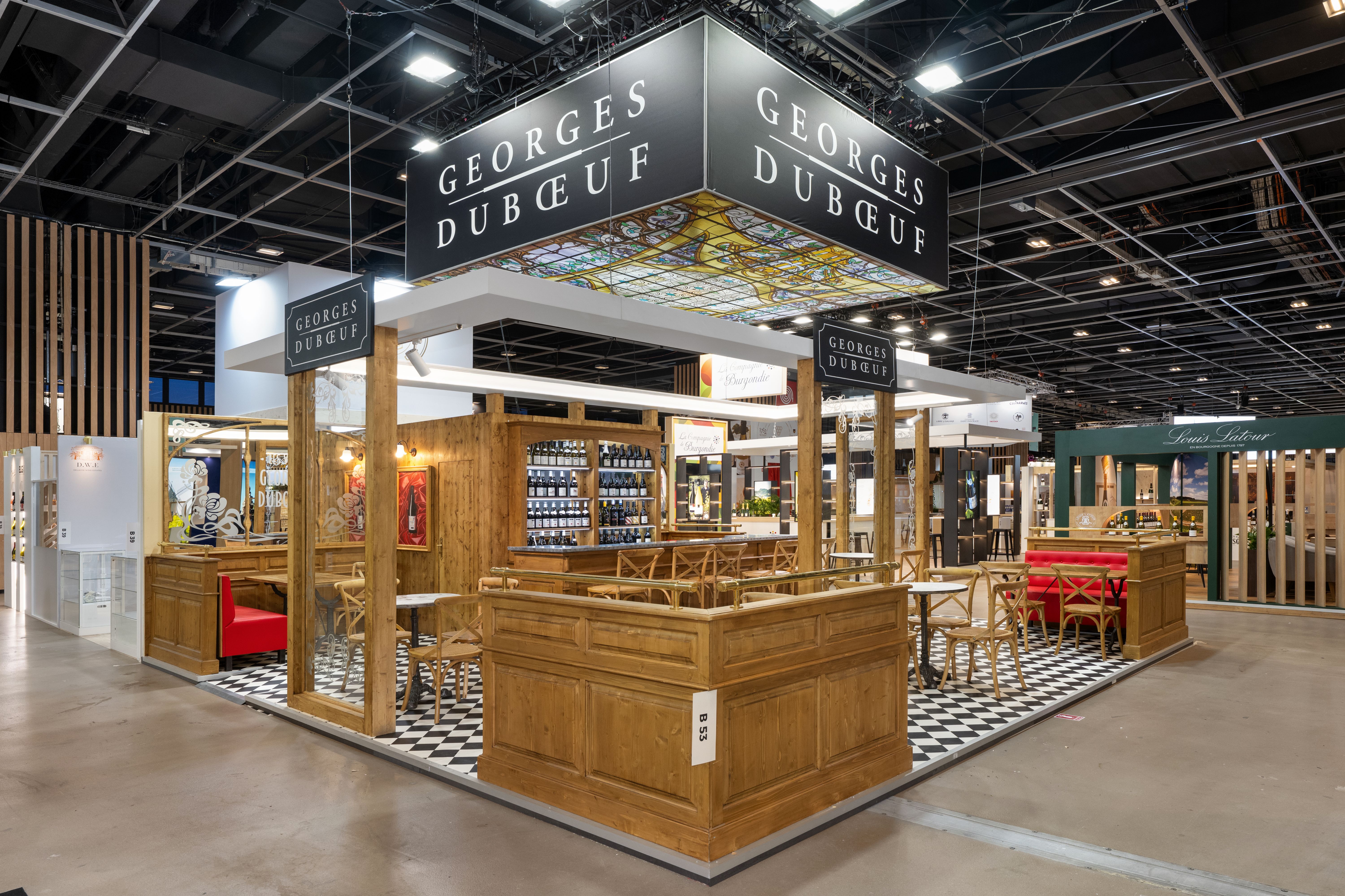 Stand Georges Dubœuf Wine Paris 2026 conçu par Expace – vue intérieure avec aménagement cave haut de gamme, présentoirs bouteilles lumineux et mobilier bois massif sur-mesure