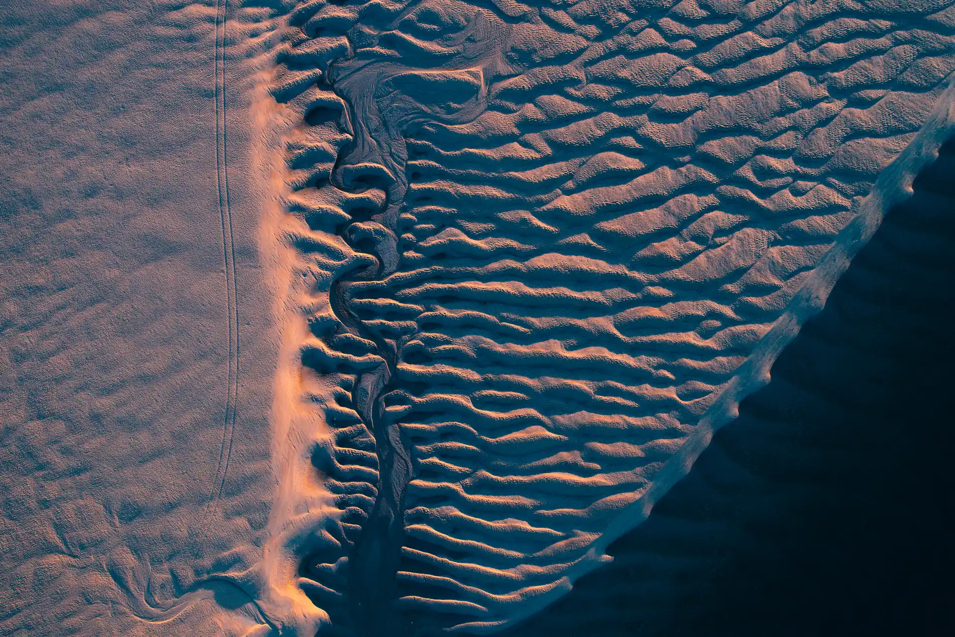 Aerial looking down on rippled tidal sand flats catching low warm light