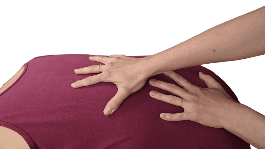 Close-up of a teacher’s two open, spread hands resting on a student’s upper back as he folds forward