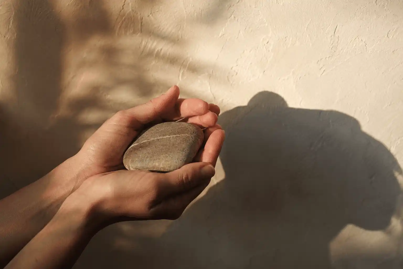 Hands holding a small round keepsake in warm subdued light