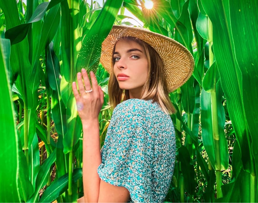 A woman in a straw hat stands in the grass