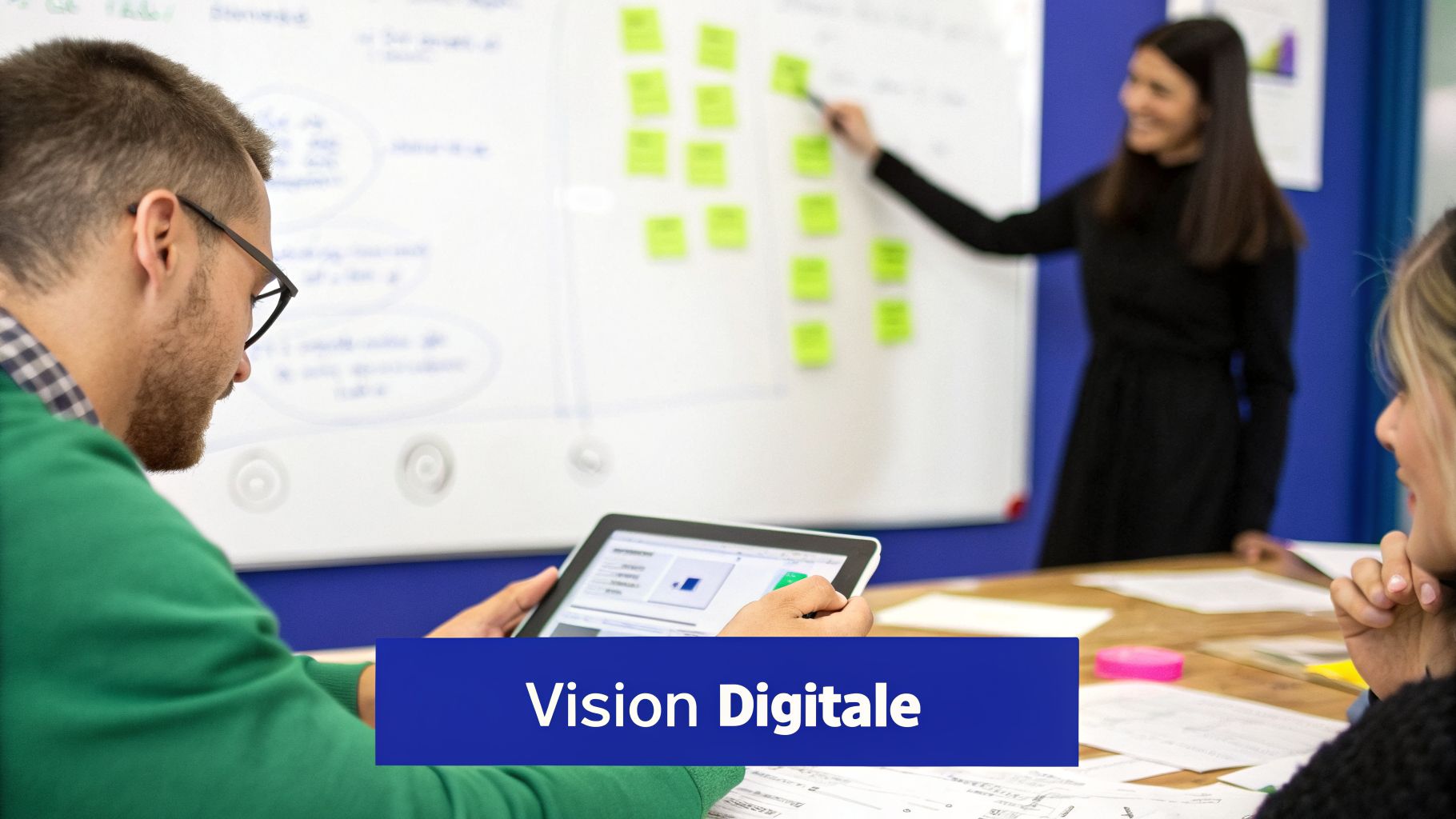 Une équipe collabore autour d'un tableau blanc et une tablette lors d'une réunion sur la transformation digitale.