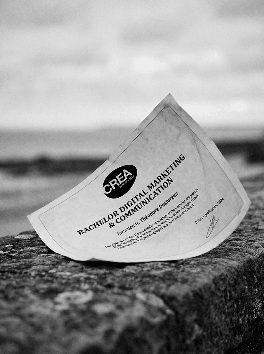 University diploma placed on a stone wall by the sea in black and white, symbolizing achievement and transition.