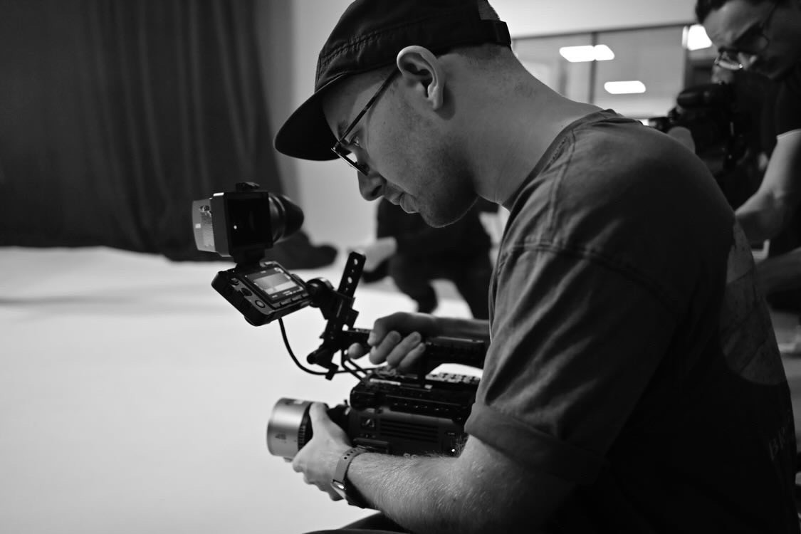 Person, holding a white rose behind his back with one arm on a light blue background