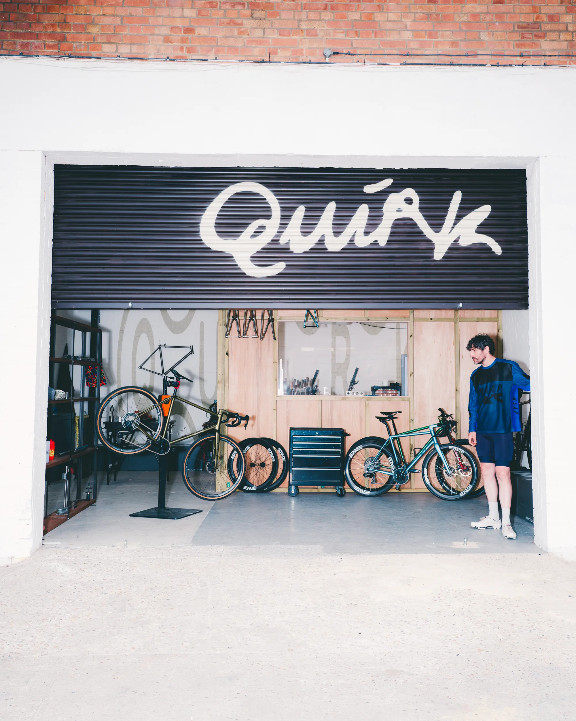 Light blue Quirk Cycles Durmitor road bike in a workshop with dark wheels
