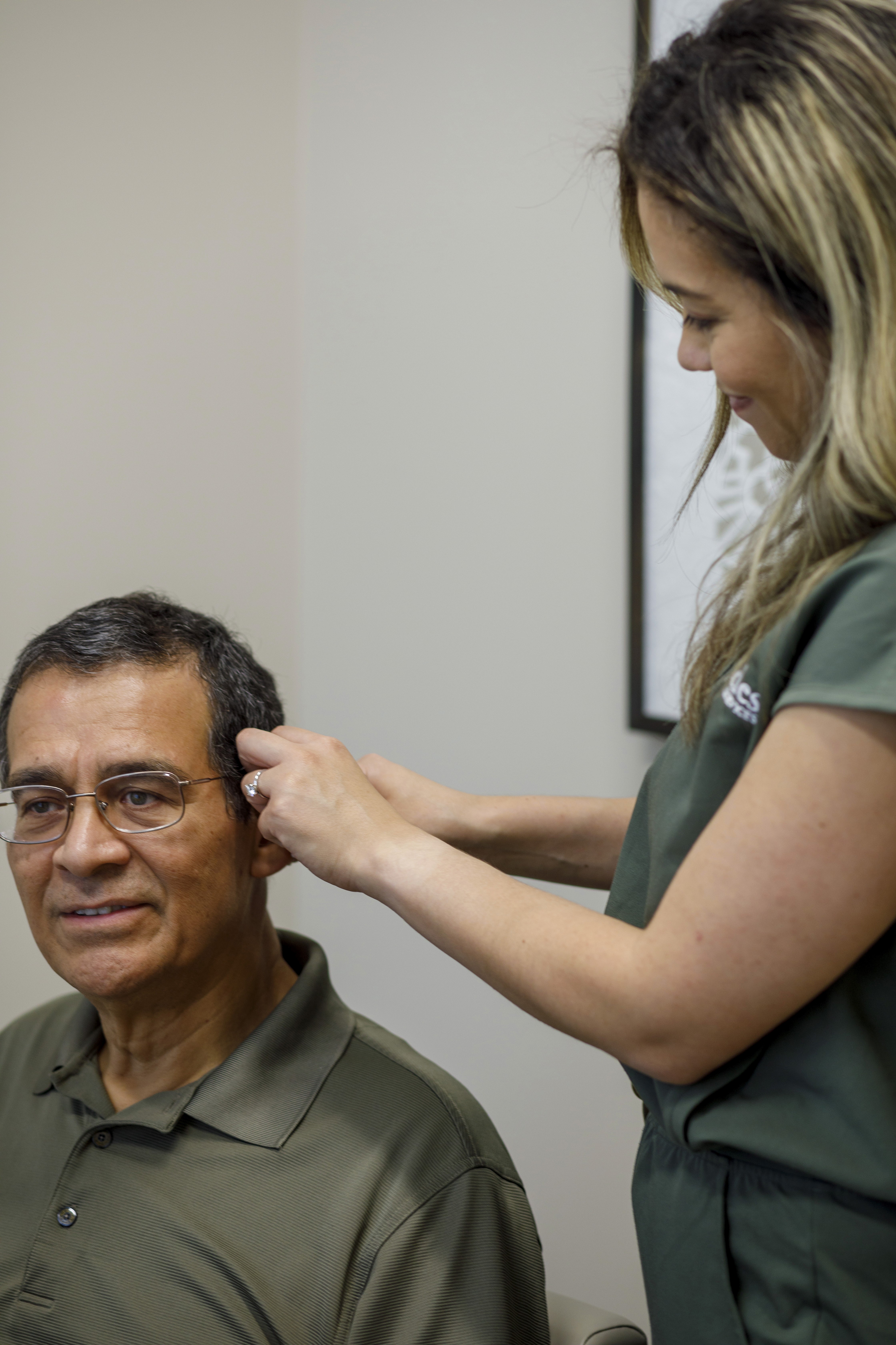 Drt Kelly Garcia fitting a hearing aid for a patient