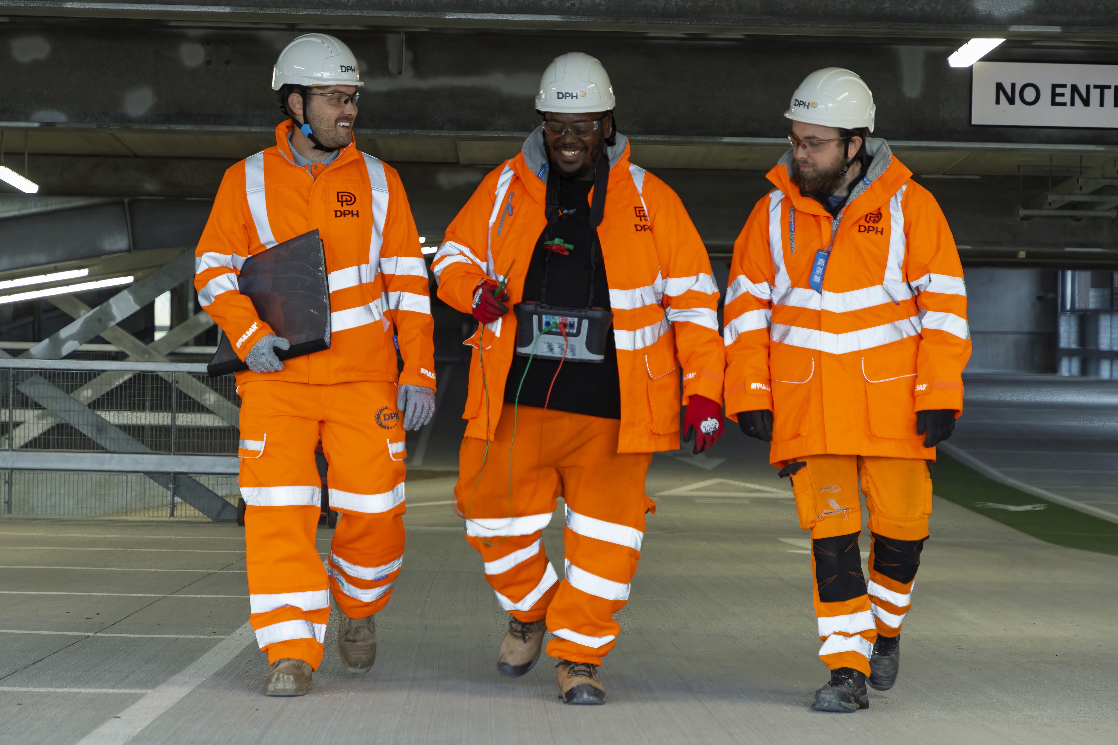 Rooftop garden with trees and plants, overlooking a cityscape at sunset with a tall building in the background
