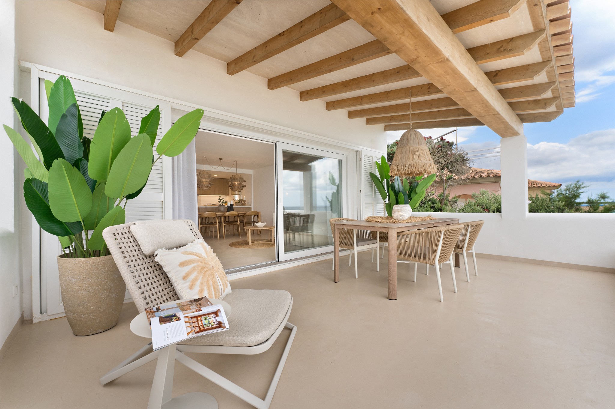 Terrasse des Beachhouse in Ses Covetes mit Holzbalken, Essbereich und Blick Richtung Küstenlandschaft Mallorcas