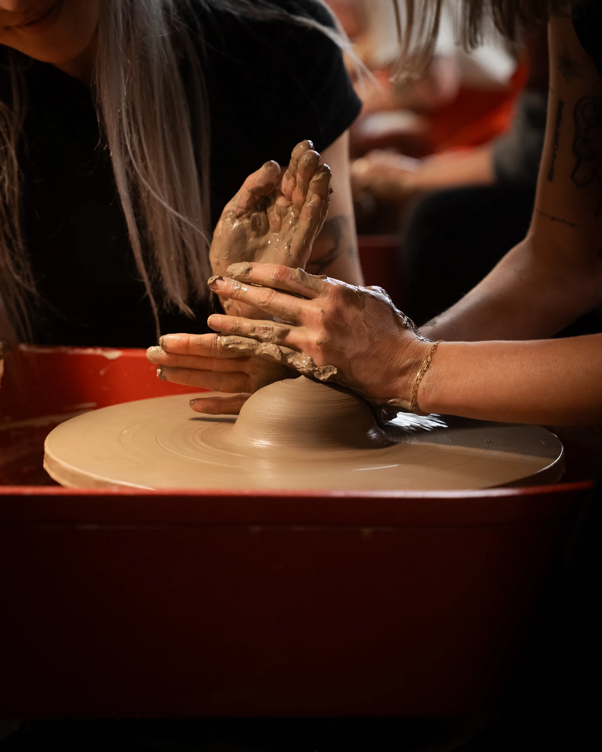 Hands centering clay on a pottery wheel during a private lesson at Kinship