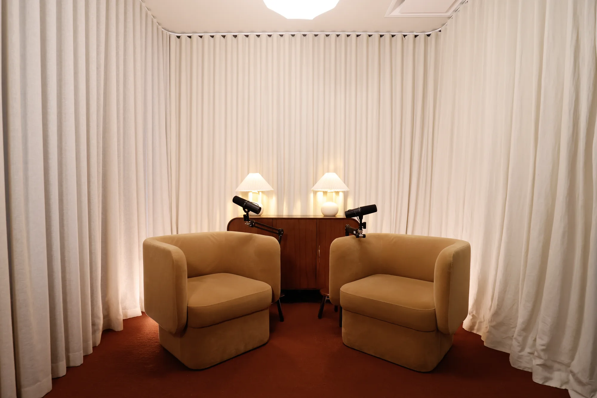 Collingwood studio's chair set — two tan armchairs facing each other with microphones, framed by cream curtains