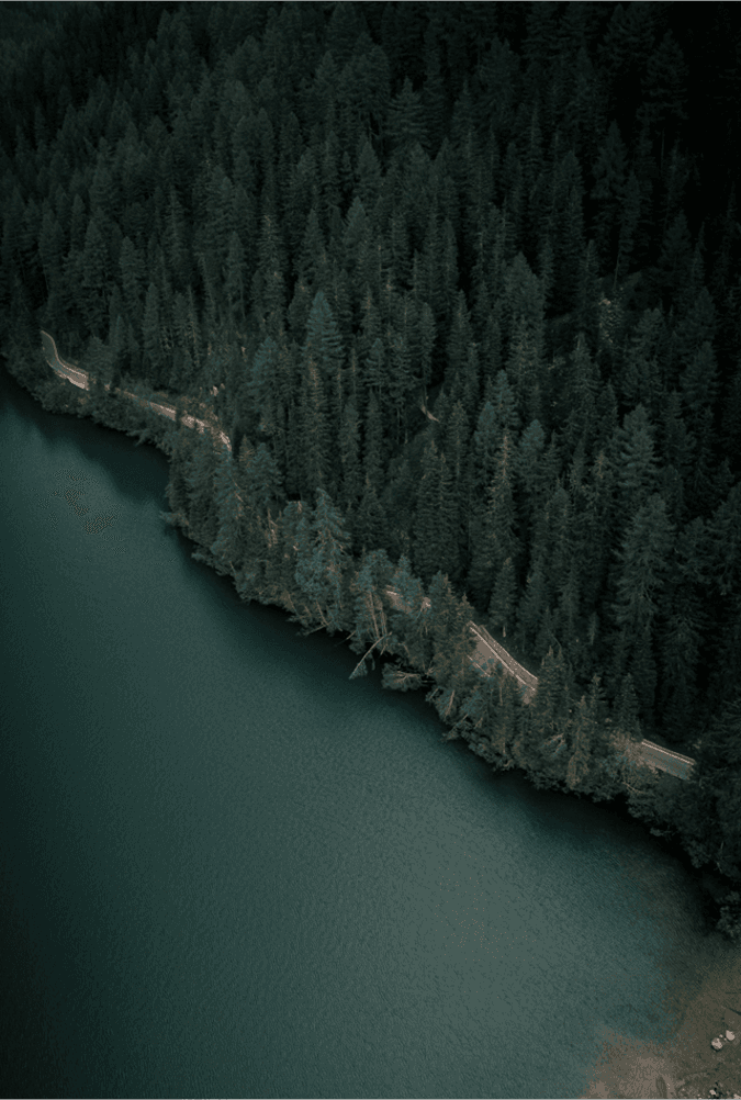 Aerial view of a winding road cutting through rocky terrain and sandy landscape.