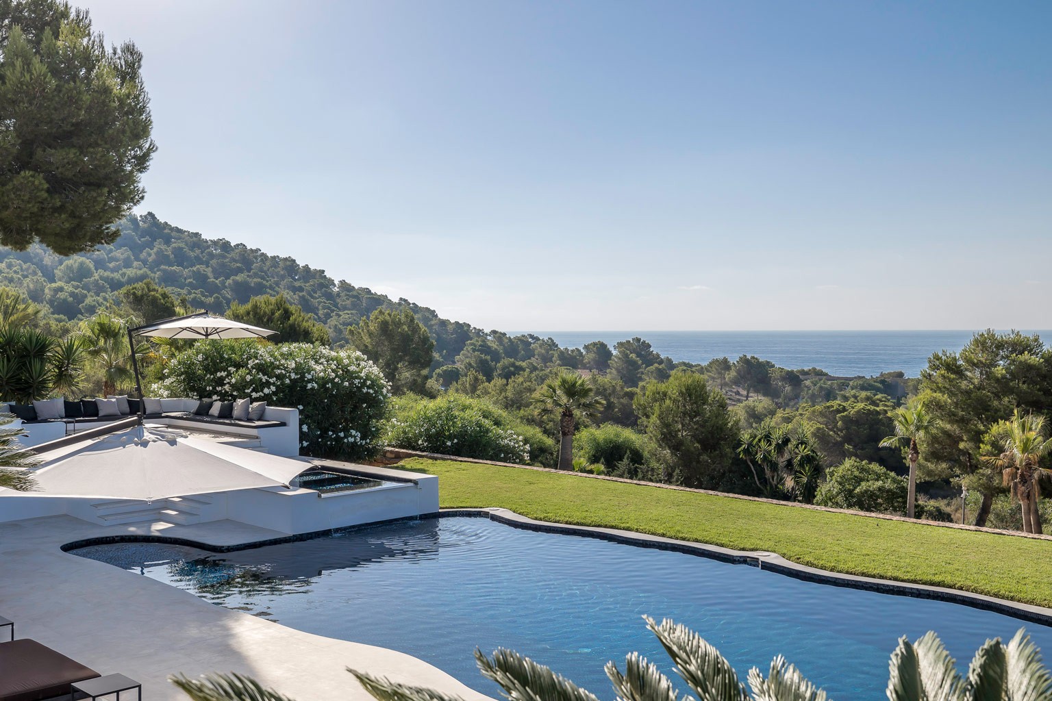 Private pool terrace overlooking Mediterranean sea and protected green nature reserve landscape.
