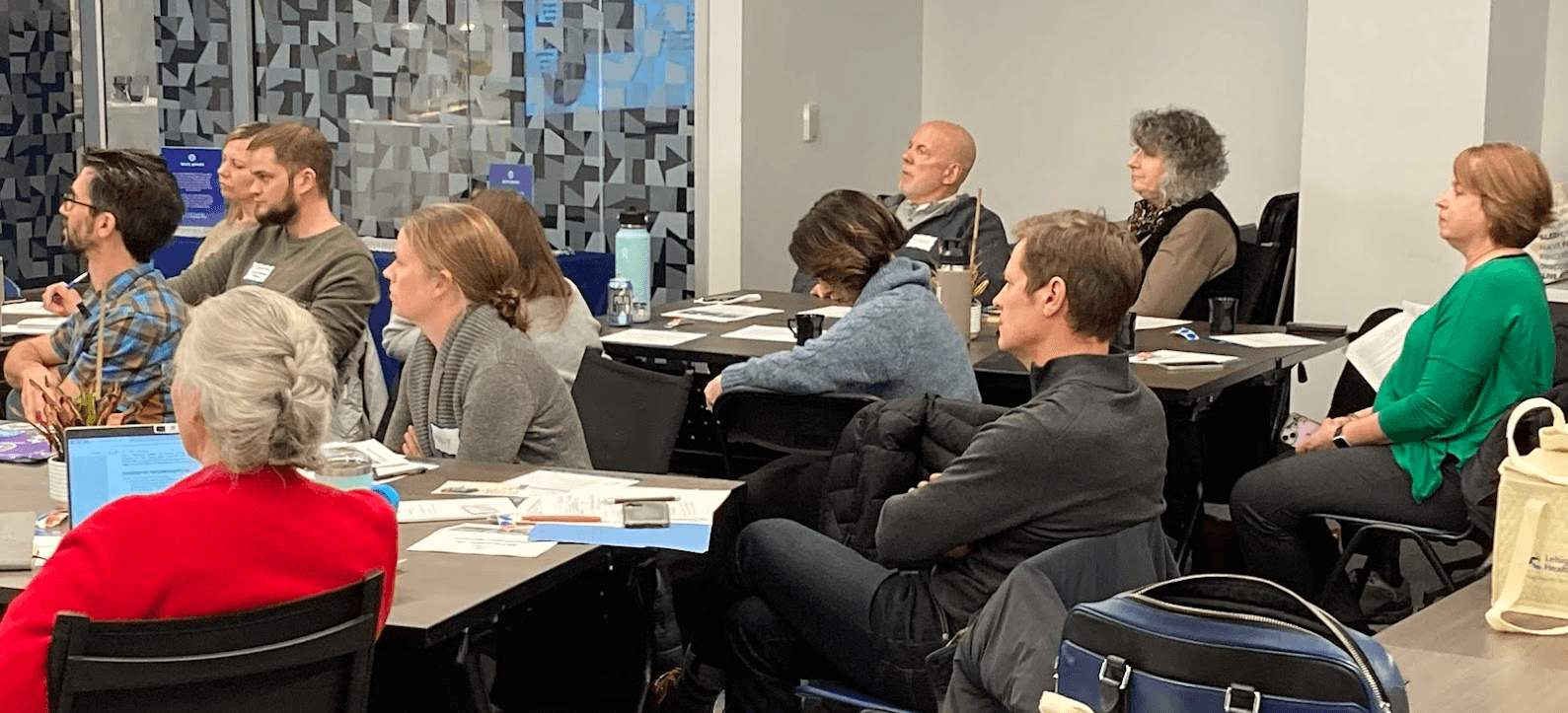Modern home office setup with a monitor, ergonomic chair, keyboard, and indoor plants near a window with blinds.