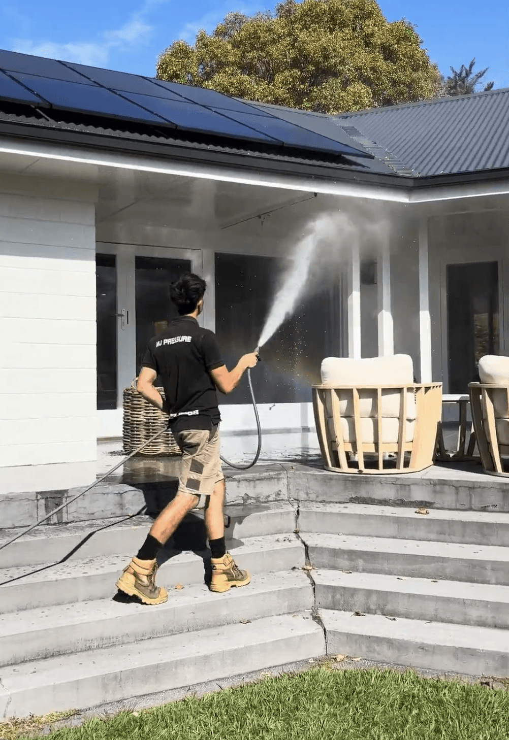 Josiah safely cleaning rooftop solar panels on a Waikato property using purified water