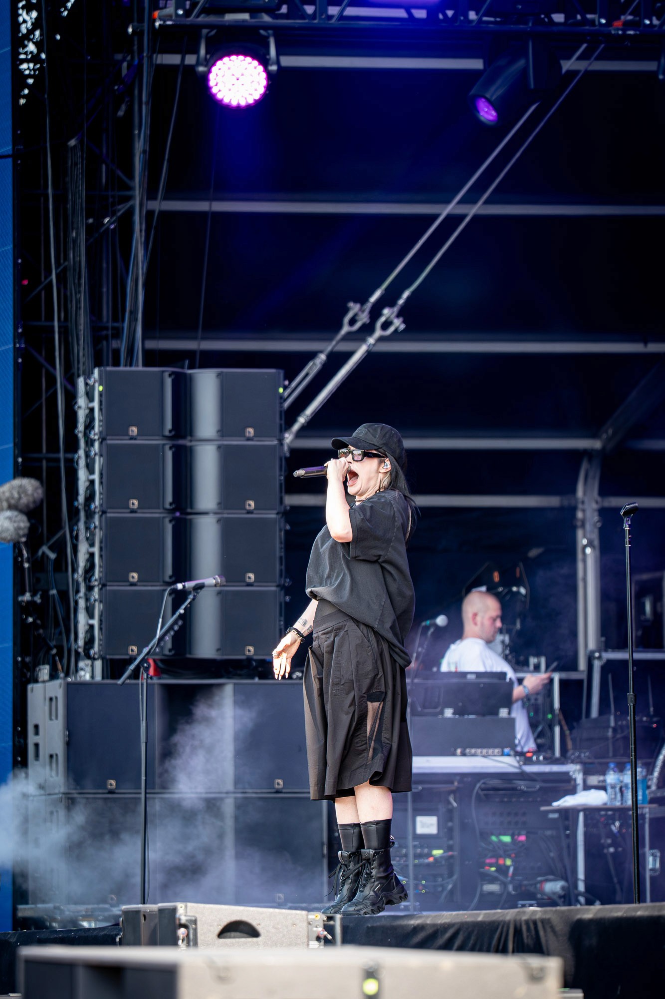 Chanteuse en noir au micro, silhouette d'un musicien en arrière-plan, éclairage bleu nocturne
