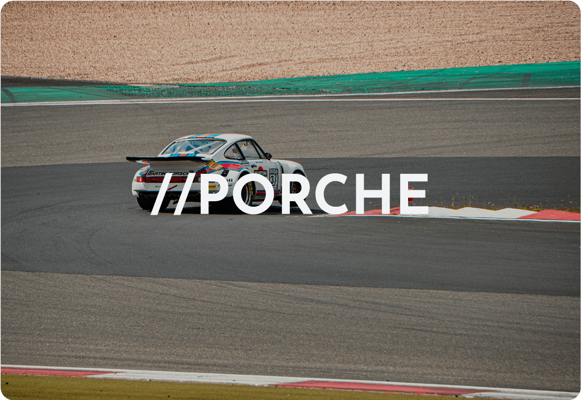 White Porsche race car racing on a track, a classic sports vehicle.