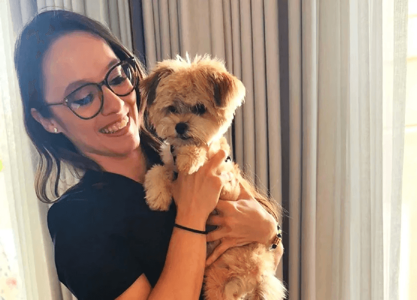 A veterinarian doing a home visit is holding a dog in her arms.