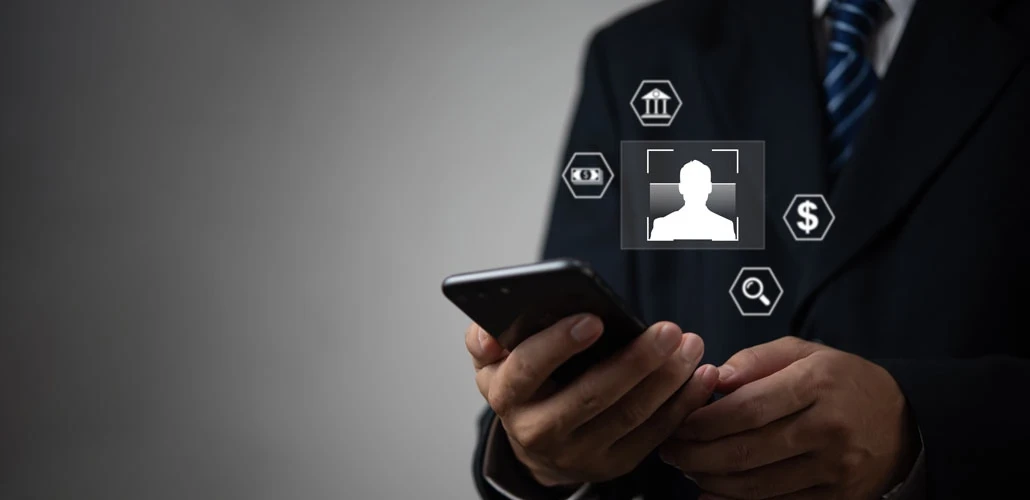 A person walks in front of large stone arches with dark doors, flanked by tall columns, in a historic building.