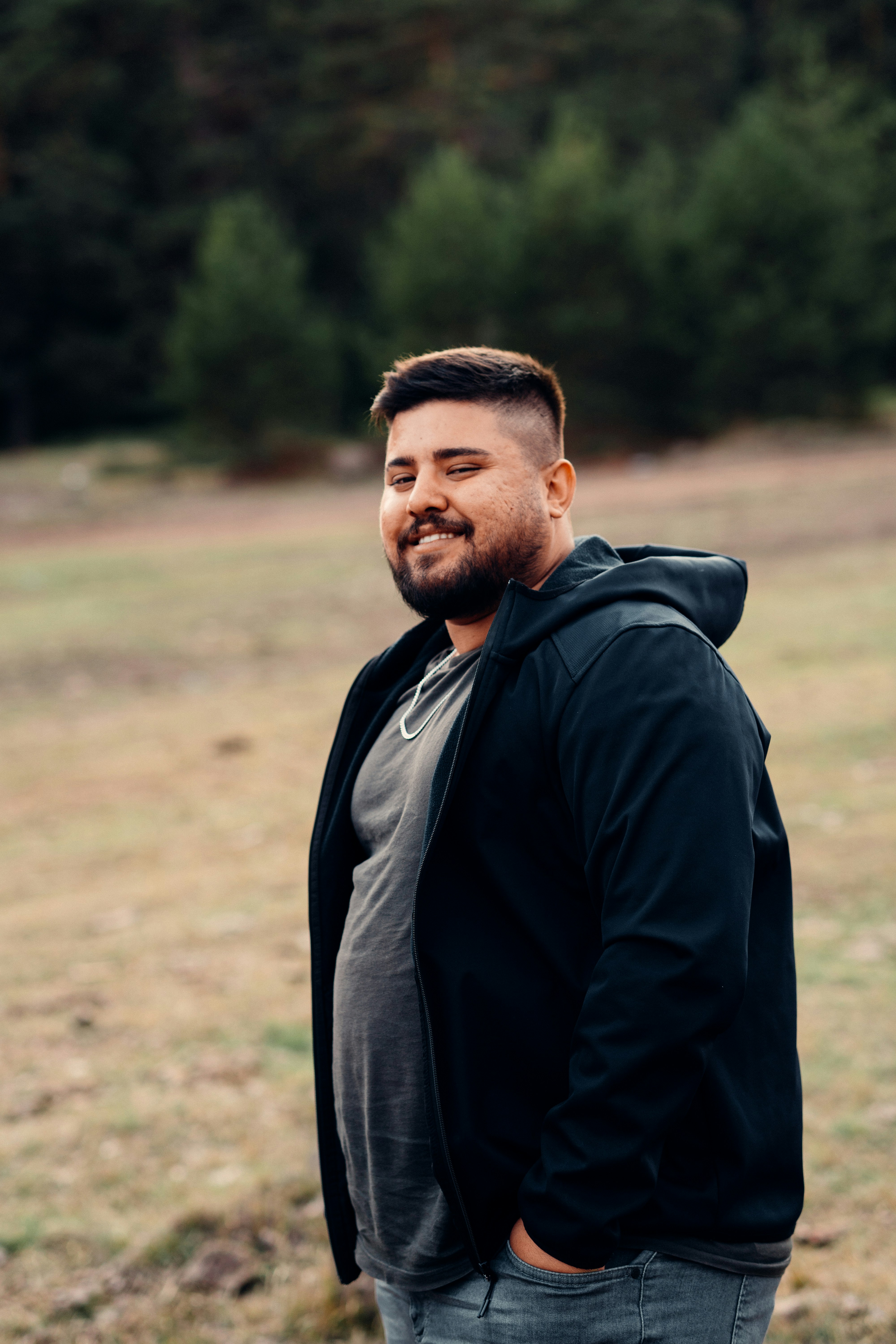 a man standing in a field with trees in the background