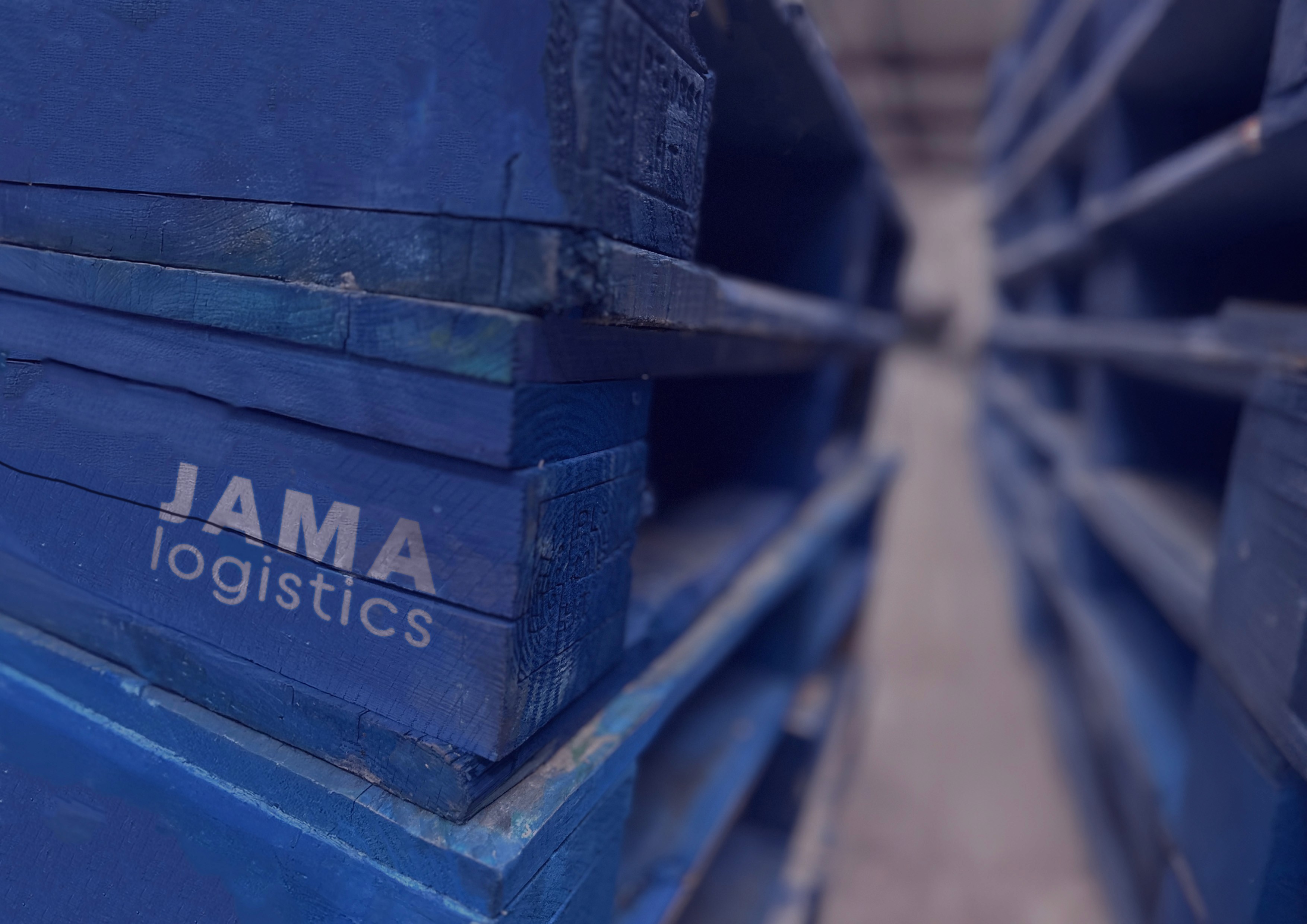 close up image of blue pallets with the jama logistics logo sprayed onto them