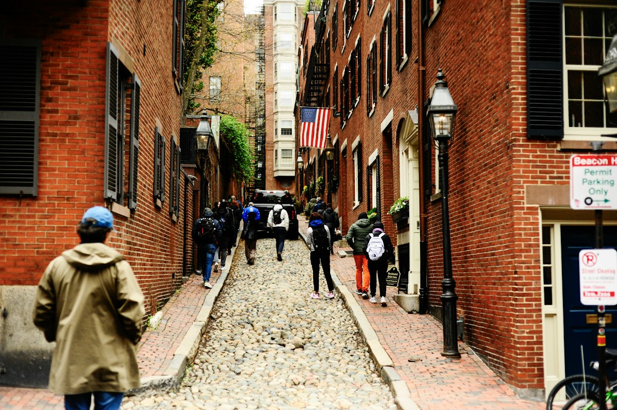 People walking up a cobblestone street lined with brick buildings