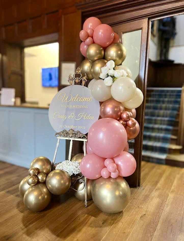 Welcome sign display framed with rose gold and ivory balloon garland at an event venue