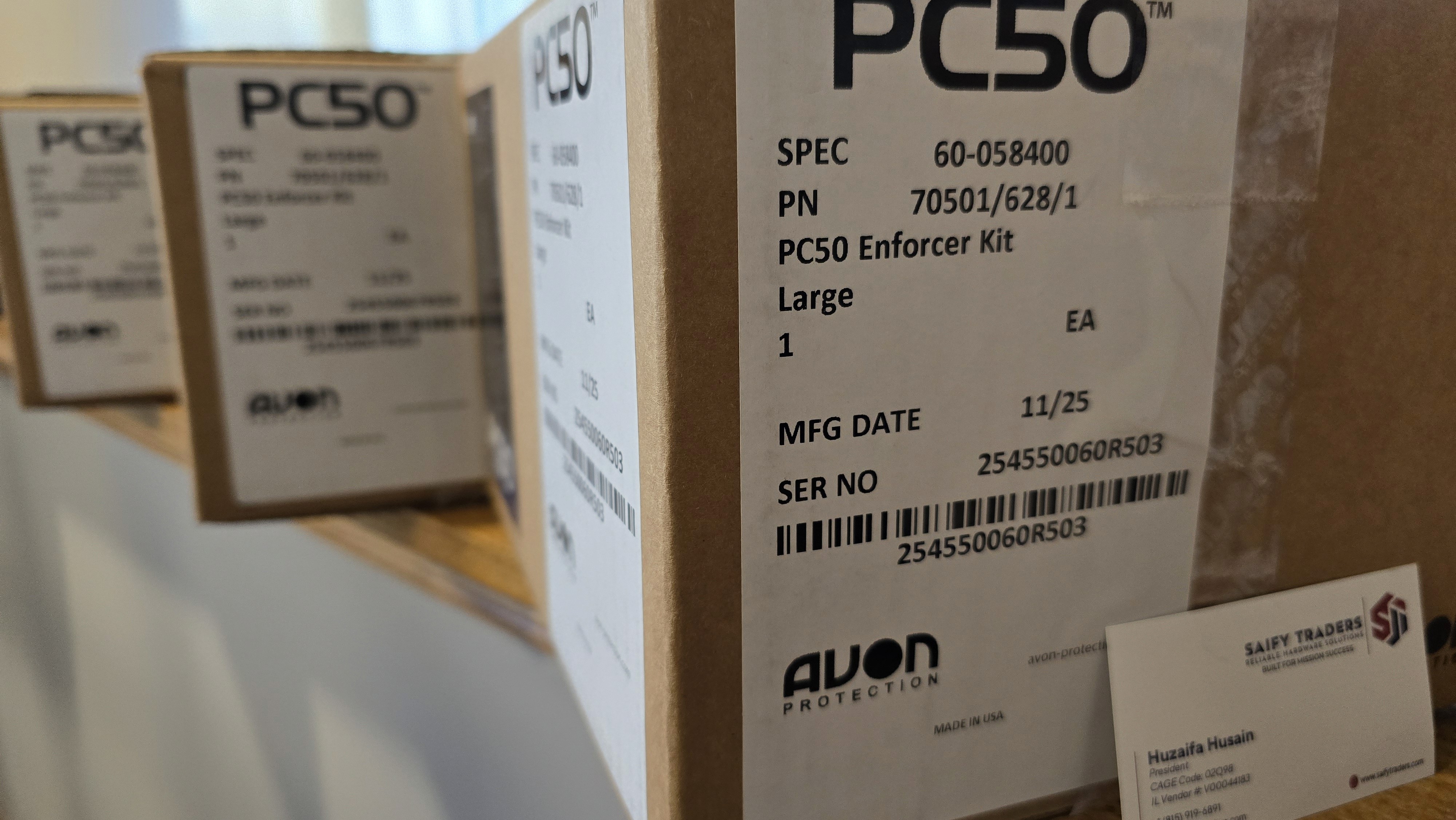 Smiling young woman with long hair standing against a dark green background, holding a finger to her chin.