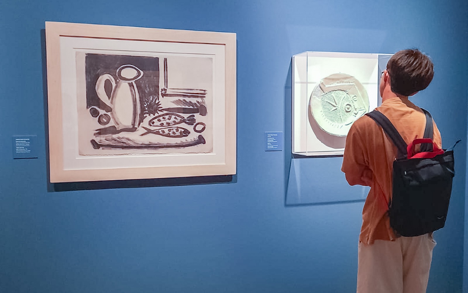 Visitor viewing art pieces in a museum exhibition.