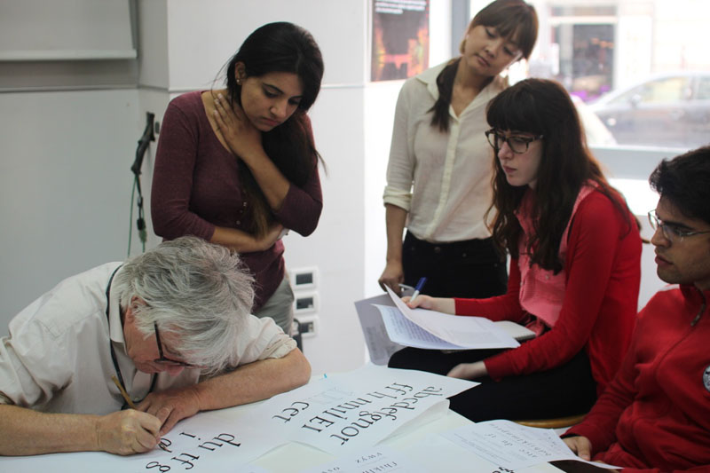 A photo of a teacher showing to the students how to draw letters.