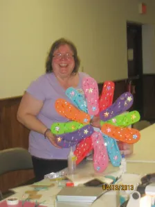 Woman holding up a colorful paper flower craft