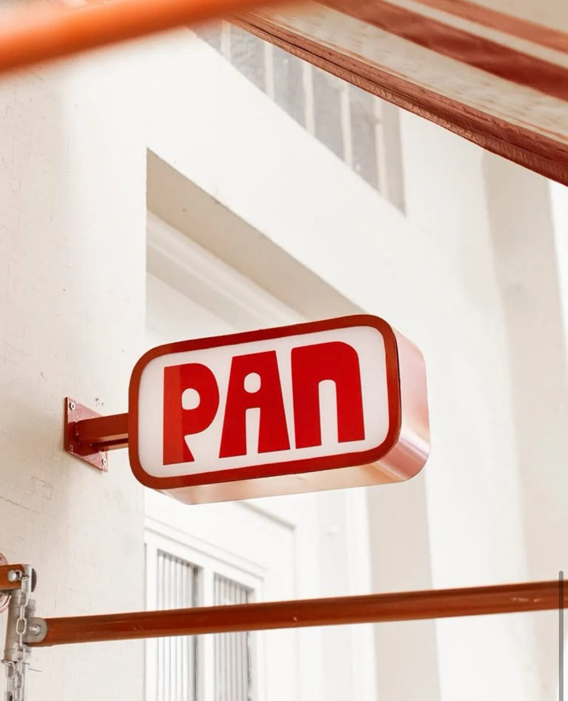 Red PAN illuminated blade sign mounted outside restaurant storefront.