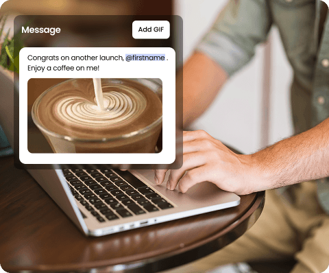 Two smiling people outdoors, one in a pink jacket holding a white phone, the other in blue with a buzz cut holding a blue phone, under a clear sky.