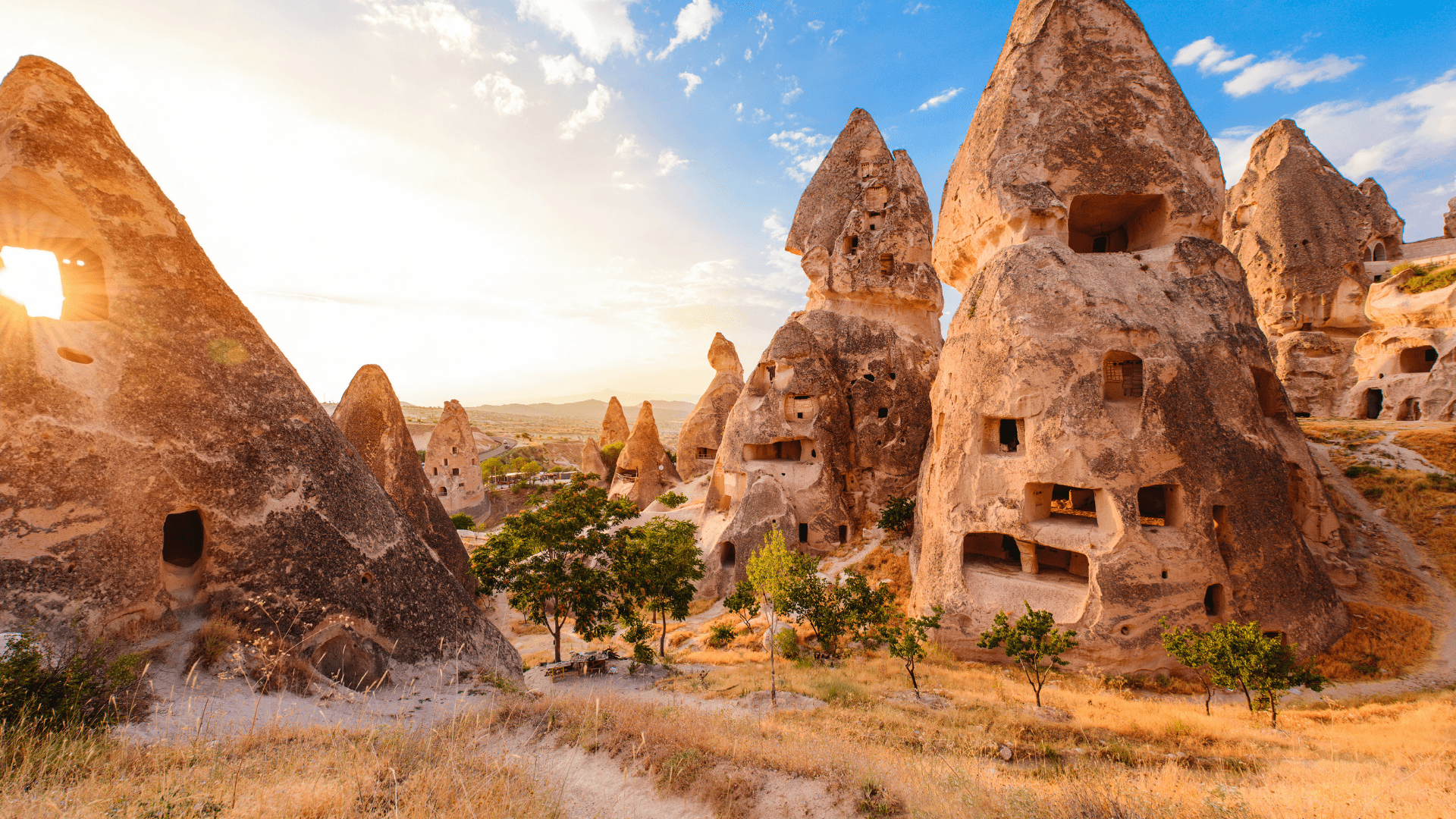 Fairy chimney rock formations and ancient cave dwellings in Cappadocia, Türkiye, breathtaking sunrise landscape with historic carved stone houses and valleys
