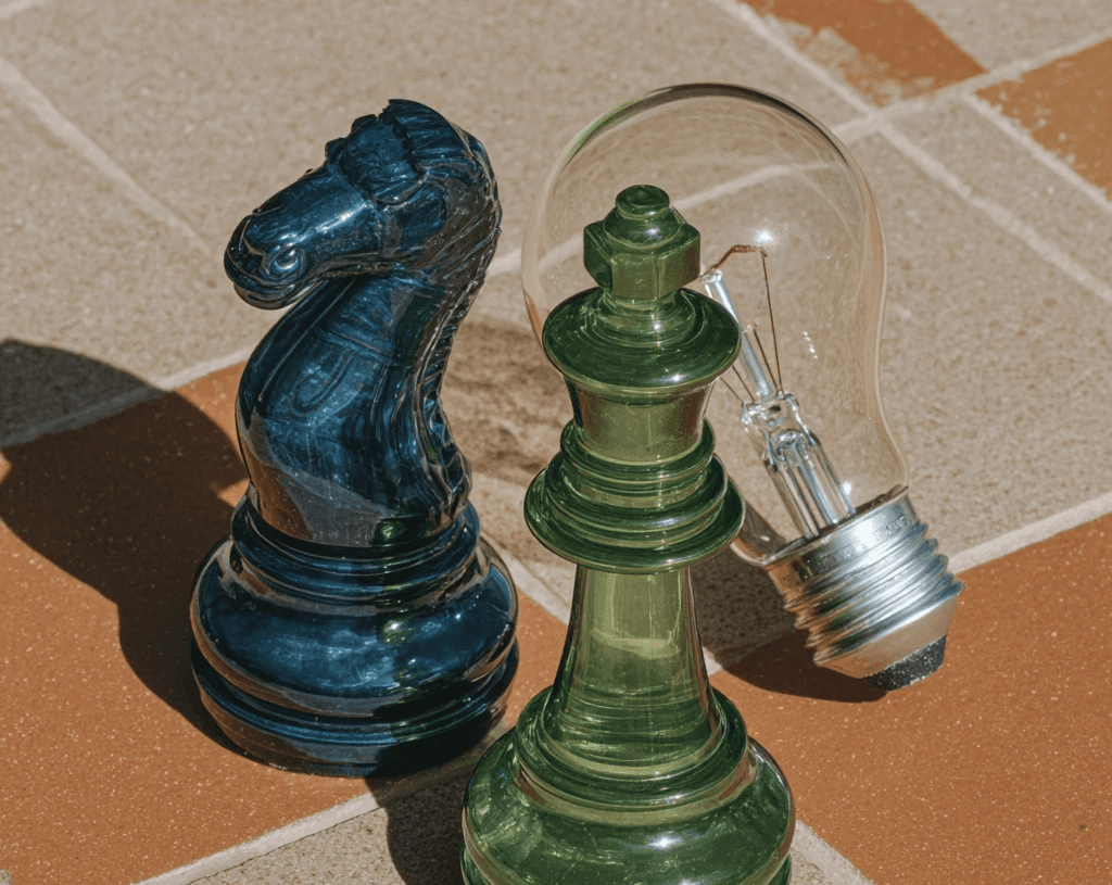 A dark blue chess knight and a green king stand beside a clear lightbulb, symbolizing strategic digital product innovation.