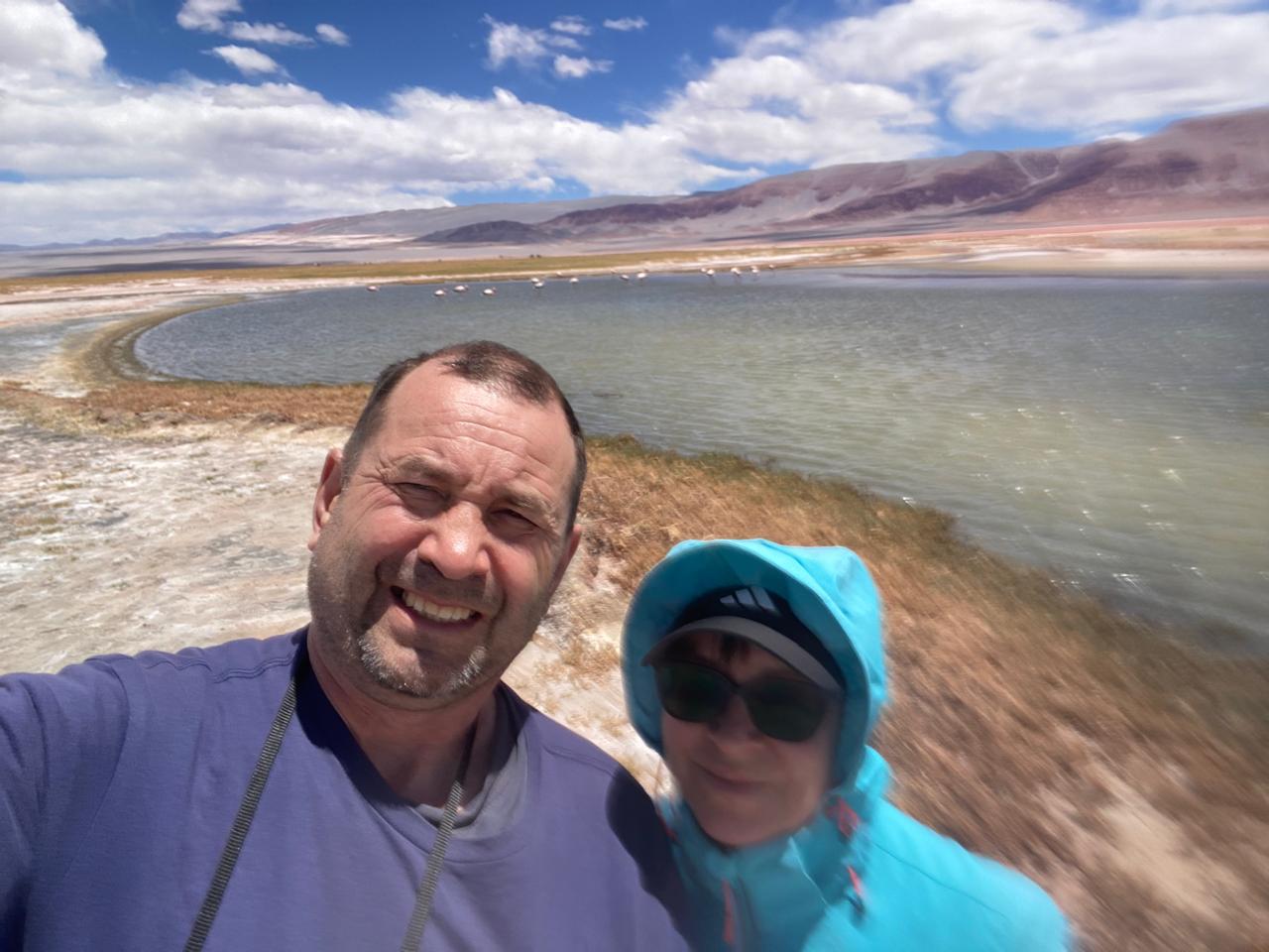 Mujer sentada sobre un tronco frente a una cascada doble en un bosque frondoso de Argentina.
