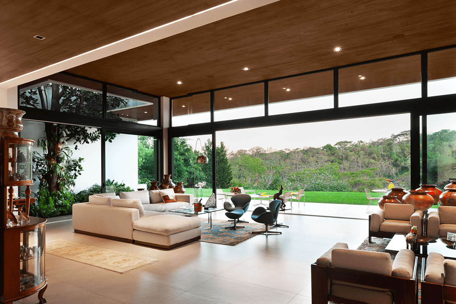 Floor-to-ceiling glazing with courtyard views and timber interior — RA House by Hurtado Arquitectos