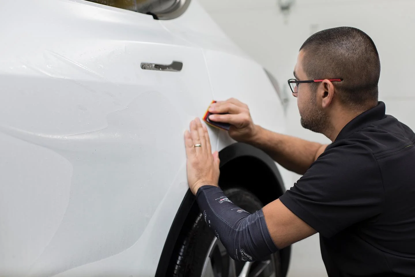 Man applying protective film to white car