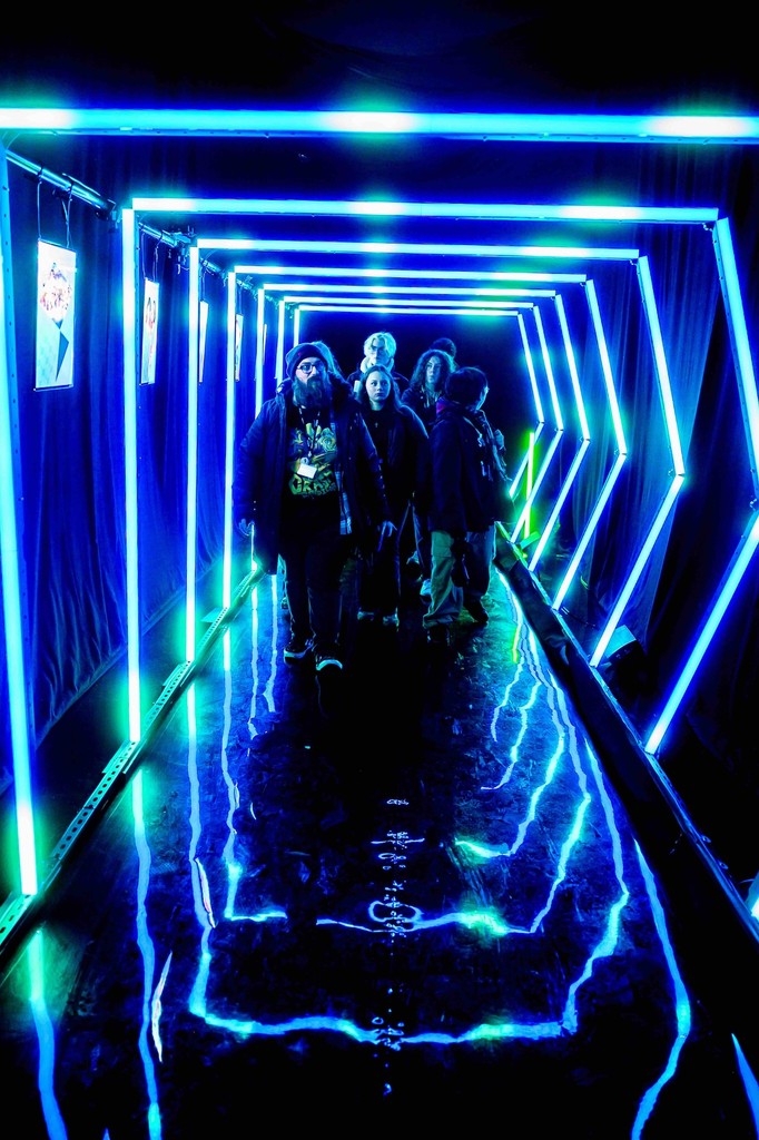 Visitors walking through the BBC UNBOXD immersive LED light tunnel, featuring blue neon frames, reflective flooring and atmospheric event production design.