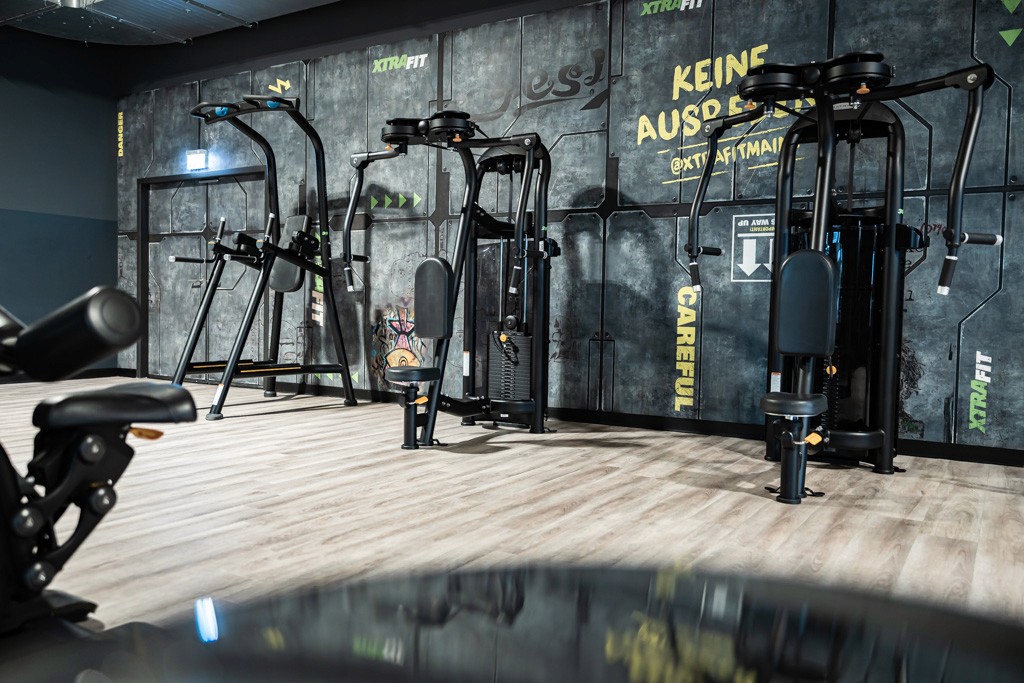 Moderner Kraft-Bereich im XTRAFIT Mainz mit Butterfly Trainingsgeräten und motivierender Wandgestaltung.