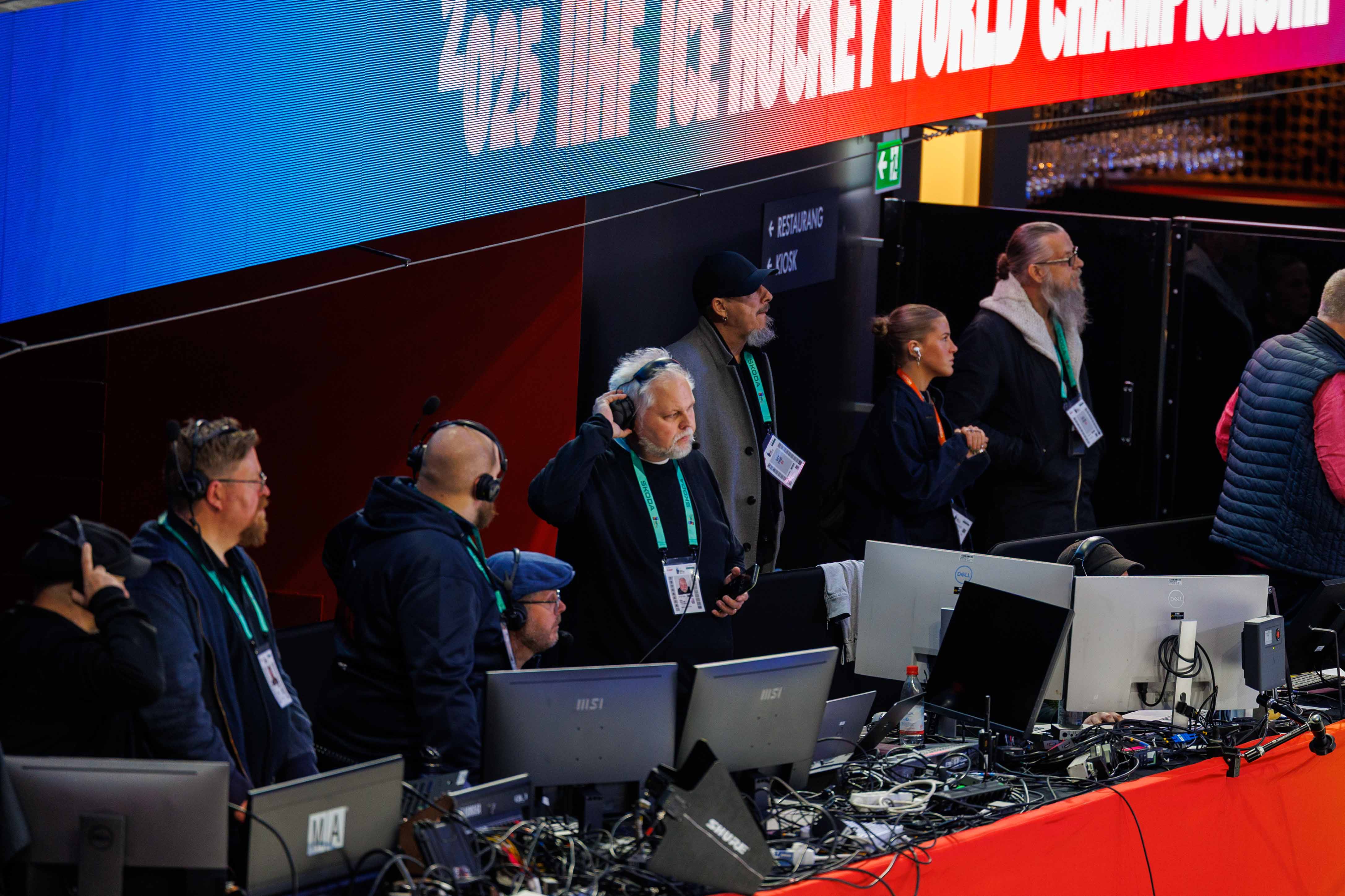 Technical crew operating from media control booths during a live broadcast at the IIHF 2025 World Championship.