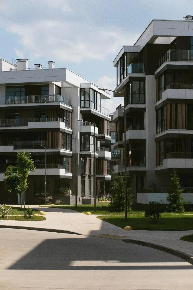Façade d'un immeuble résidentiel contemporain et neuf avec des balcons et des espaces végétalisés au pied du bâtiment.