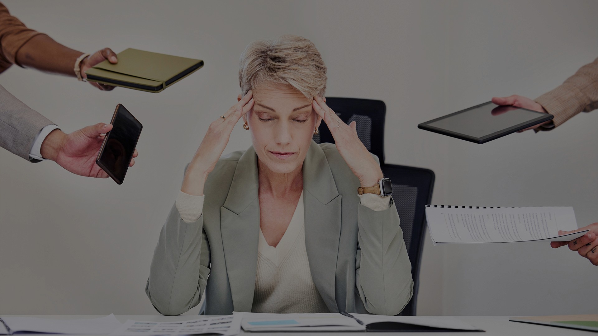 Overwhelmed manager under workplace pressure as multiple tasks and devices compete for attention, representing leadership stress and manager overload in modern organisations.