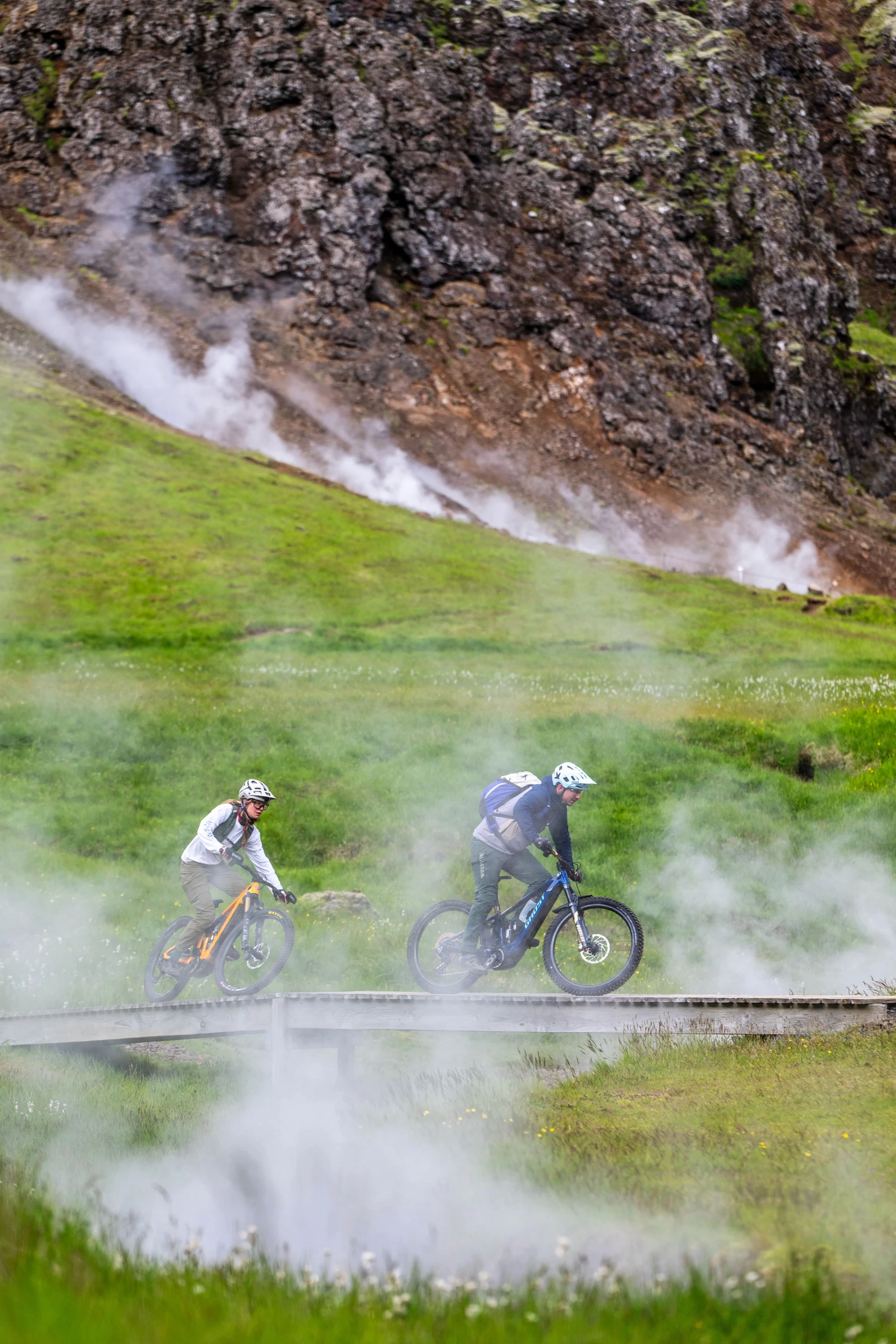 two mountain bike riders through geothermal steam
