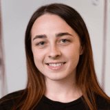 Smiling young woman with brown hair, in a black shirt, looking at the camera.