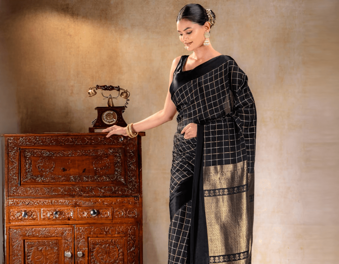 A woman wearing a black crepe saree with delicate golden borders from That Saree Shop, highlighting the saree’s fluid drape and refined craftsmanship for an elegant, modern look.