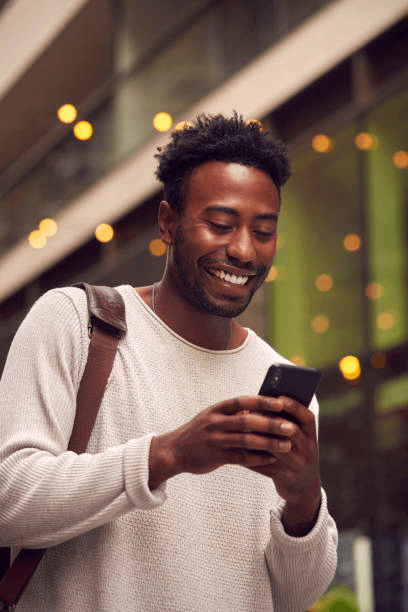 photo of a man smiling while looking at his phone